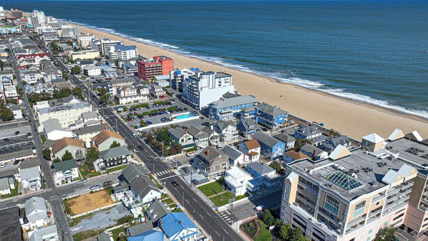 An aerial view of a coastal town with a beach, buildings, and roads.