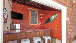 A bar with stools, a chalkboard menu, and a television mounted on the wall.