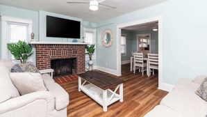 A living room with a fireplace, a television, and a ceiling fan.
