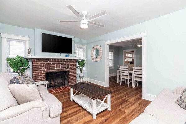 Una sala de estar con chimenea, televisor y ventilador de techo.