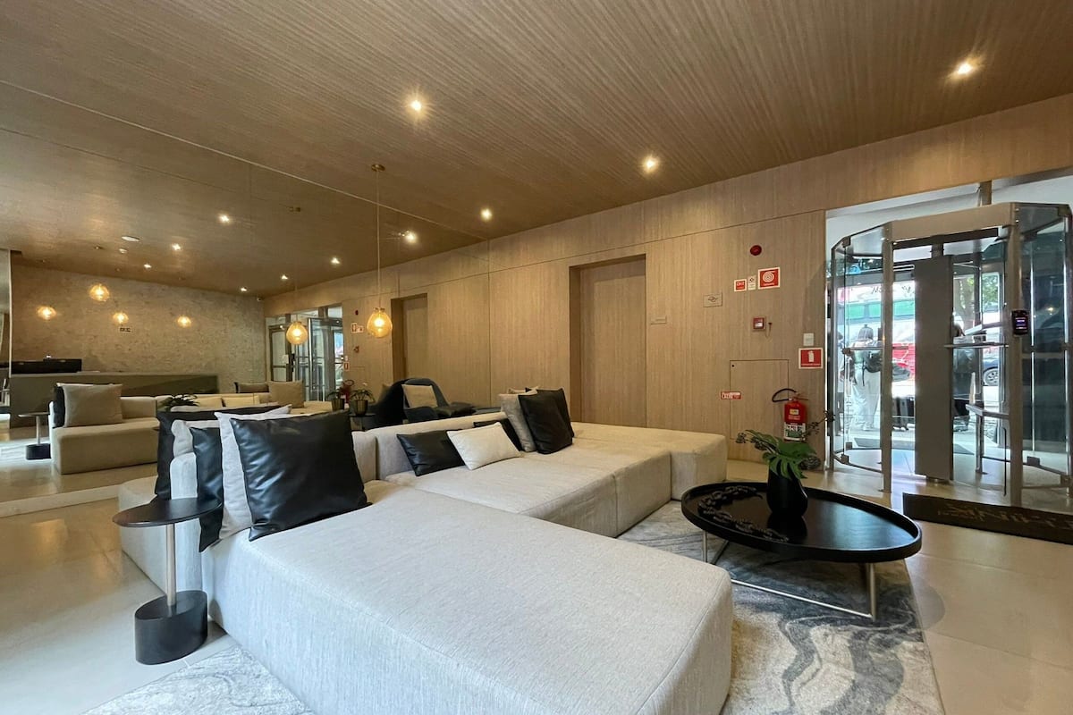 Een moderne hotel lobby met een zithoek, een receptiebalie en een draaideur.