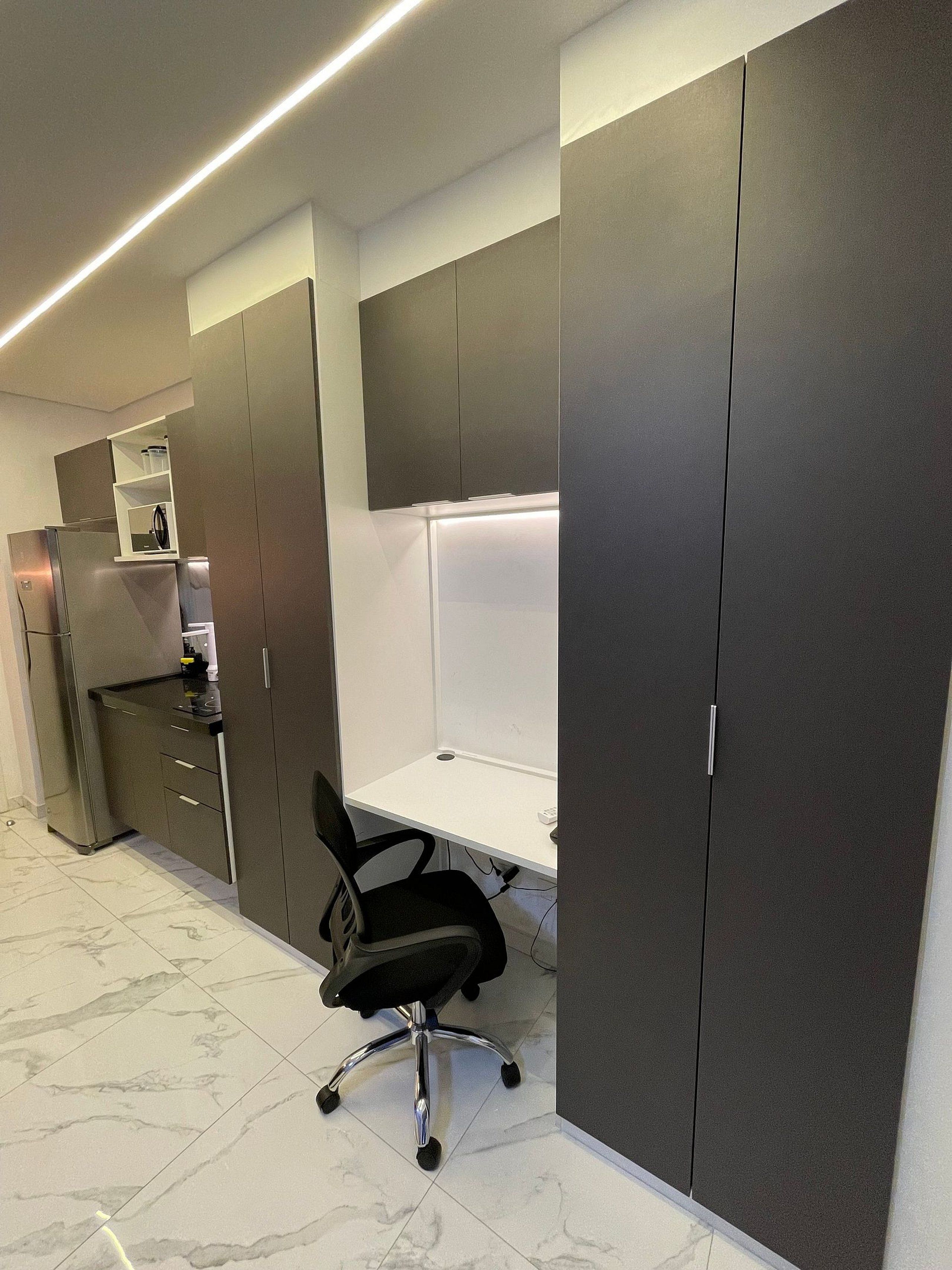 A modern office space with a desk, chair, and built-in cabinets.