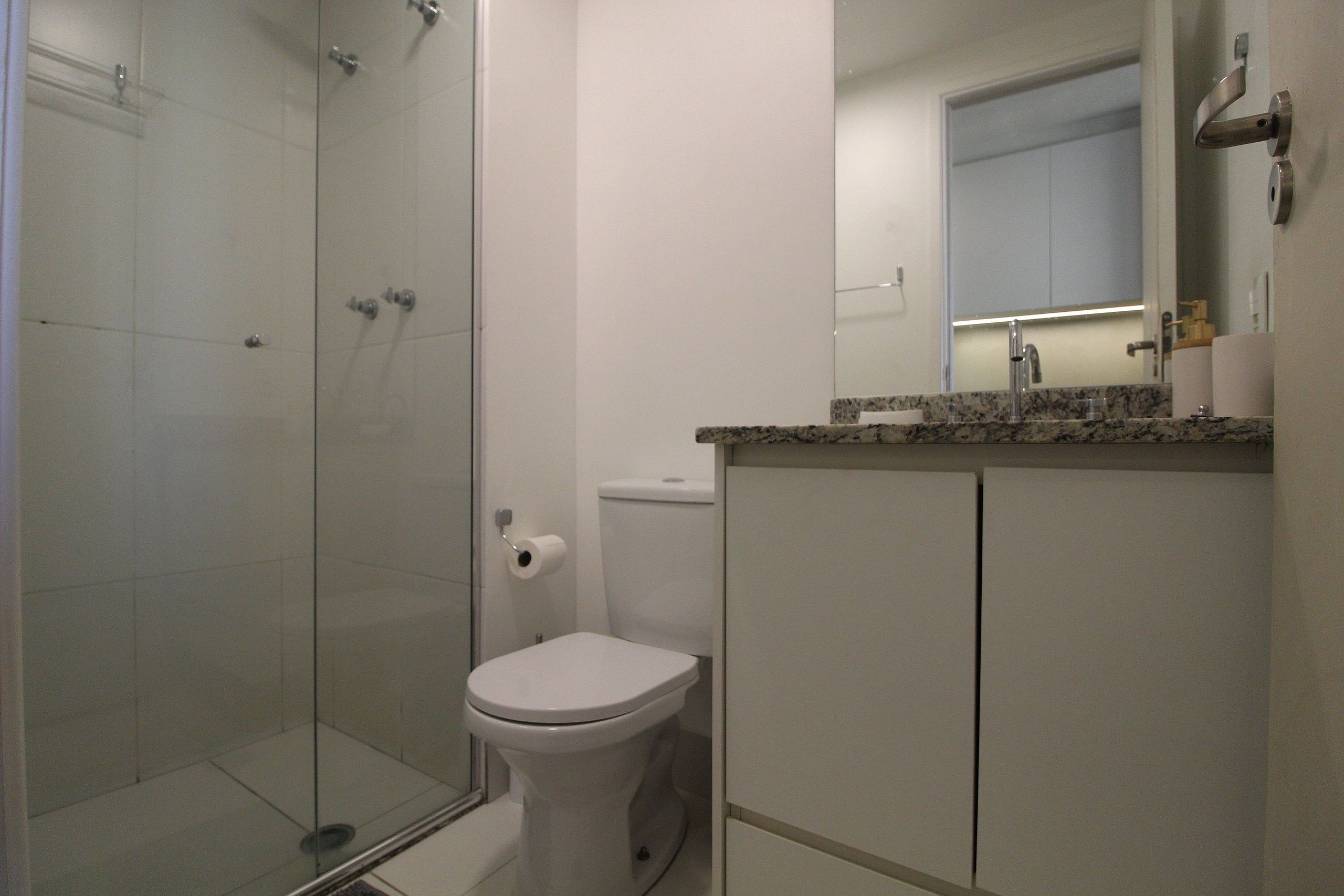 Un baño con cabina de ducha de vidrio, inodoro y encimera de mármol.