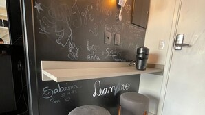 Een modern interieur met een prikbord, twee grijze krukken, een houten toonbank en een deur.