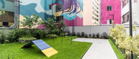 A courtyard with a grassy area, a pathway, and a colorful mural on a building.