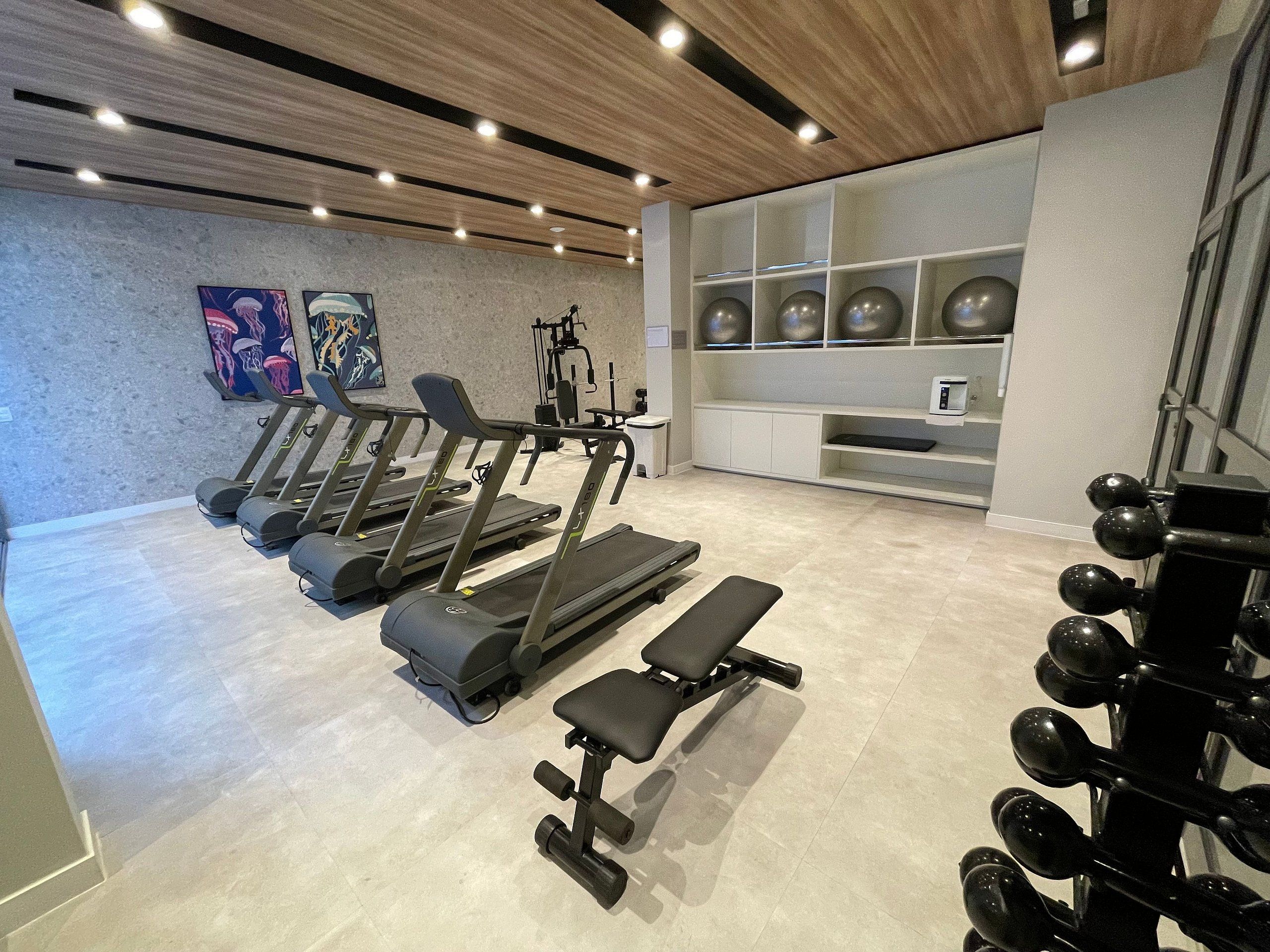 A gym with treadmills, a bench, and a weight rack.