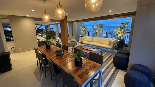 Una sala de estar moderna con una mesa de comedor de madera, sofás e iluminación colgante.