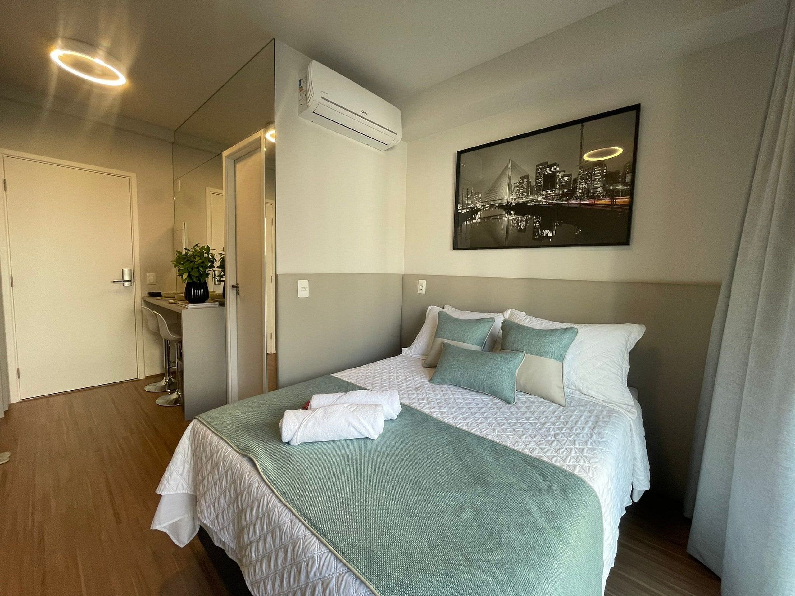 A hotel room with a bed, a bathroom, and a cityscape view.