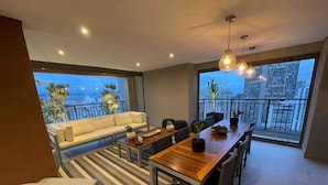 Un comedor moderno con mesa de madera, sillas, sofá y plantas en macetas.