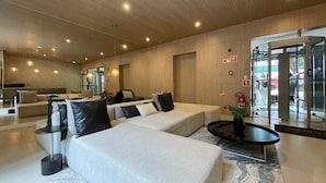 A modern lobby with sofas, a coffee table, and a revolving door. - Prime Stay - Vila Buarque - São Paulo - BR (São Paulo)