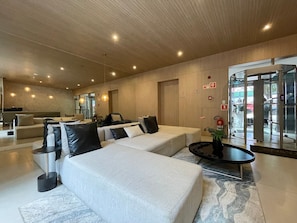 A modern lobby with sofas, a coffee table, and a revolving door.