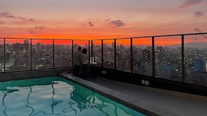 Una piscina en la azotea con vista a la ciudad al atardecer.
