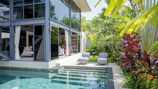 Ett modernt hus med en glasfasad, en swimmingpool och en uteplats.