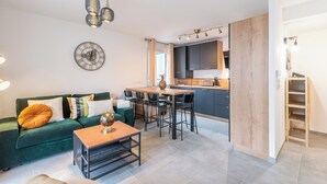 Una sala de estar moderna con un sofá verde, una mesa de centro y un comedor con mesa y sillas de madera.