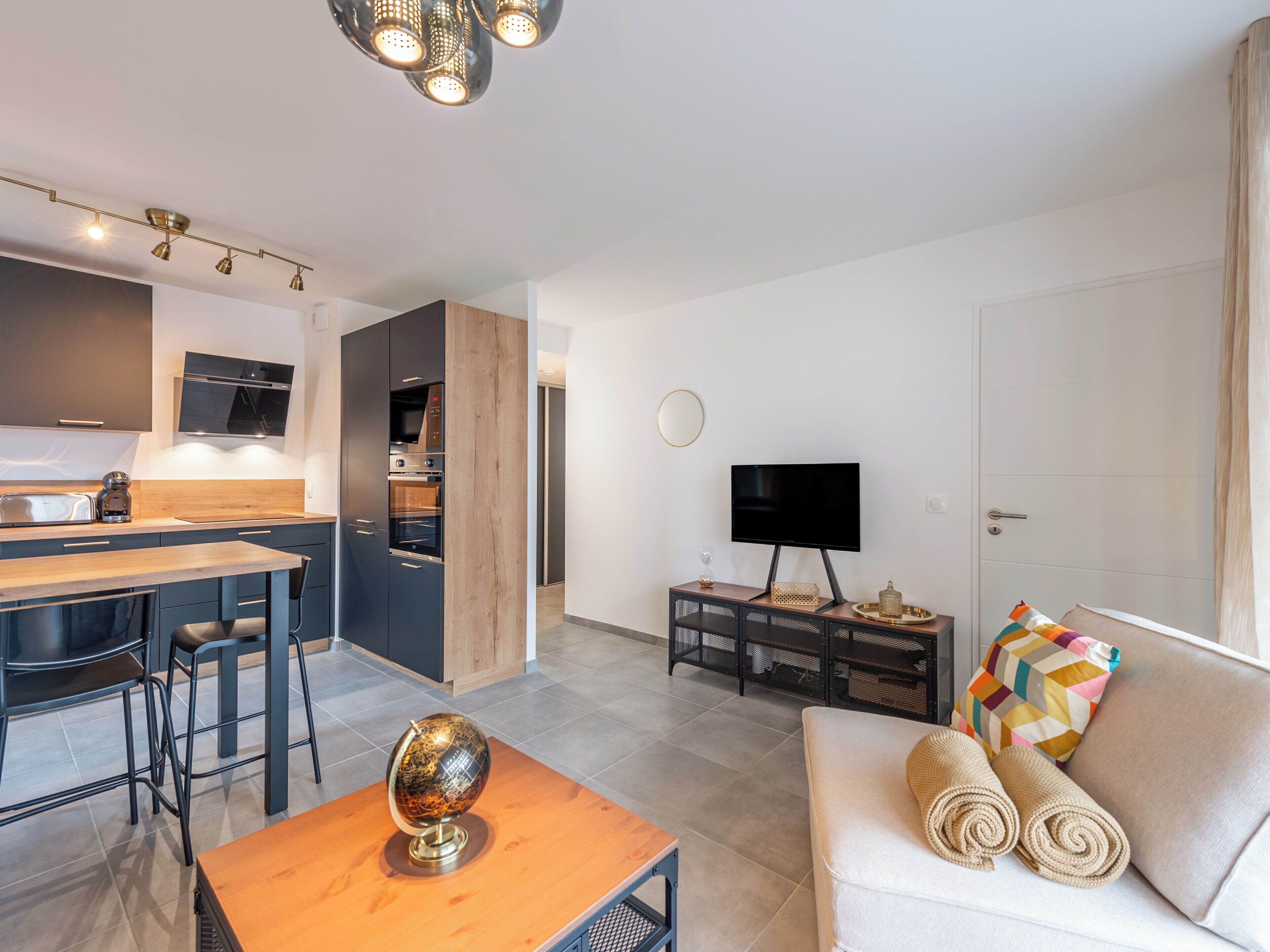 Eine moderne Wohnung mit Küche, Essbereich, Wohnzimmer und Fernseher.