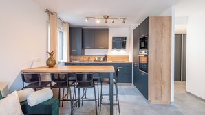 Una cocina moderna con una isla de madera, armarios oscuros y un horno empotrado.