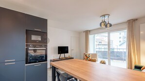 Una cocina moderna con armarios oscuros, una mesa de comedor de madera y un televisor de pantalla plana.