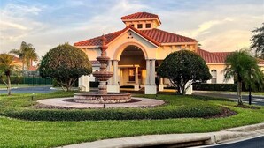 A building with a red-tiled roof, a central fountain, and a well-manicured lawn. - Newly Renovated Vacation Home in Tuscan Hills with Private Pool Near Disney! (Davenport)
