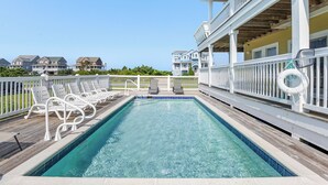 A swimming pool with white lounge chairs and a wooden deck. - Calypso: Semi-Soundfront w/ Pool | Wind Over Waves (Salvo)