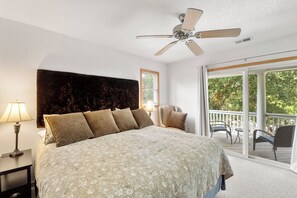 Relax in this serene retreat with a large bed, ceiling fan, and balcony overlooking lush greenery.