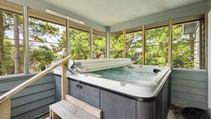 Un jacuzzi en un área exterior cubierta, con un banco de madera y un cartel que indica el clima.