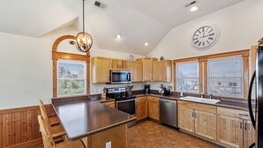 A kitchen with wooden cabinets, a central island, stainless steel appliances, and a clock on the wall. - Ocean's 11: Private Pool | Hot Tub | Game Room (Salvo)