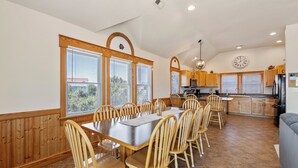 A spacious kitchen with wooden cabinets, a dining table with chairs, and a large window with blinds. - Ocean's 11: Private Pool | Hot Tub | Game Room (Salvo)