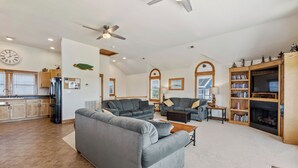 A spacious living area with a large gray sofa, a fireplace, and a bookshelf. - Ocean's 11: Private Pool | Hot Tub | Game Room (Salvo)