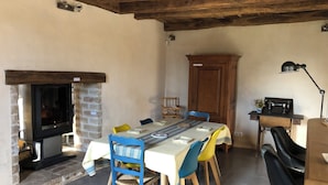 A rustic dining area with a stone fireplace, wooden ceiling beams, and a table set for four.