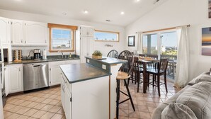 A kitchen with white cabinets, a dishwasher, and a dining area with a table and chairs.