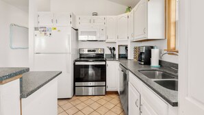 A compact kitchen with white cabinets, a stainless steel oven, a microwave, and a coffee maker.