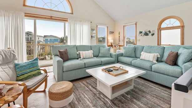 A spacious living room with a large sectional sofa, a white coffee table, and a view of the outside. - Terrapin Station: Private Pool | Oceanside (Corolla)