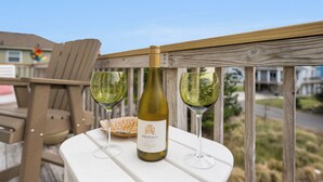 A bottle of Arvail wine and two glasses on a white table outdoors. - Terrapin Station: Private Pool | Oceanside (Corolla)