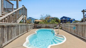 A swimming pool with a wooden deck and a wooden fence surrounding it. - Terrapin Station: Private Pool | Oceanside (Corolla)