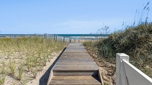 Een houten looppad dat naar een strand leidt, met een hek op de achtergrond.