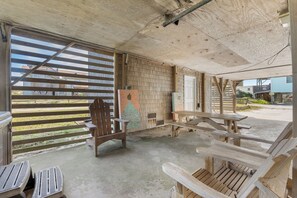 Relax on the patio with comfortable benches and chairs, surrounded by a wooden fence and a large window.