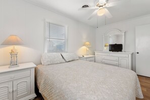 Relax in this serene bedroom with a large bed, ceiling fan, and flat-screen TV.
