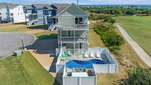 Un immeuble à plusieurs étages doté d’une piscine et d’un espace extérieur aménagé, entouré d’un parcours de golf et offrant une vue sur l’océan.