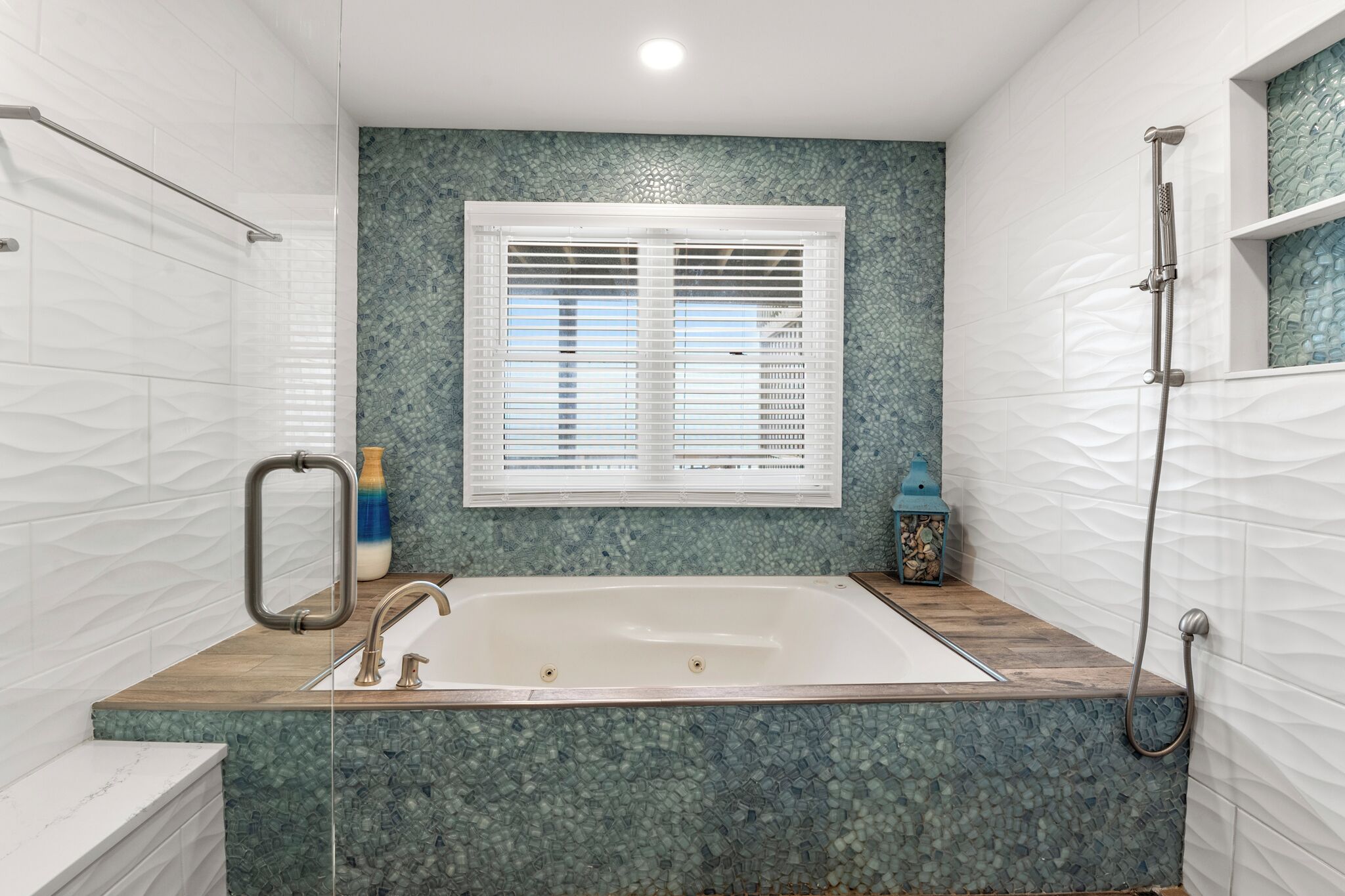 Une salle de bain avec une baignoire, une douche et une fenêtre avec des stores.