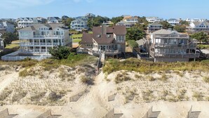 A coastal residential area with multiple two-story houses featuring balconies and large windows. - Chirality: Oceanfront | Direct Beach Access (Duck)