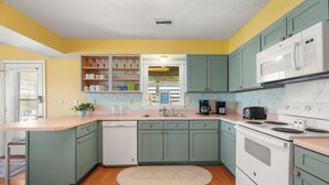 A kitchen with teal cabinets, a white dishwasher, a stove, and a microwave. - It's A Shore Thing: Ocean Views | Hot Tub | Dogs OK (Rodanthe)