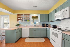 A kitchen with teal cabinets, a white dishwasher, a stove, and a microwave.