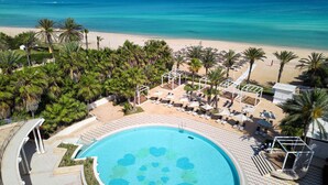 Ein Resort mit Pool, Strand und Palmen.