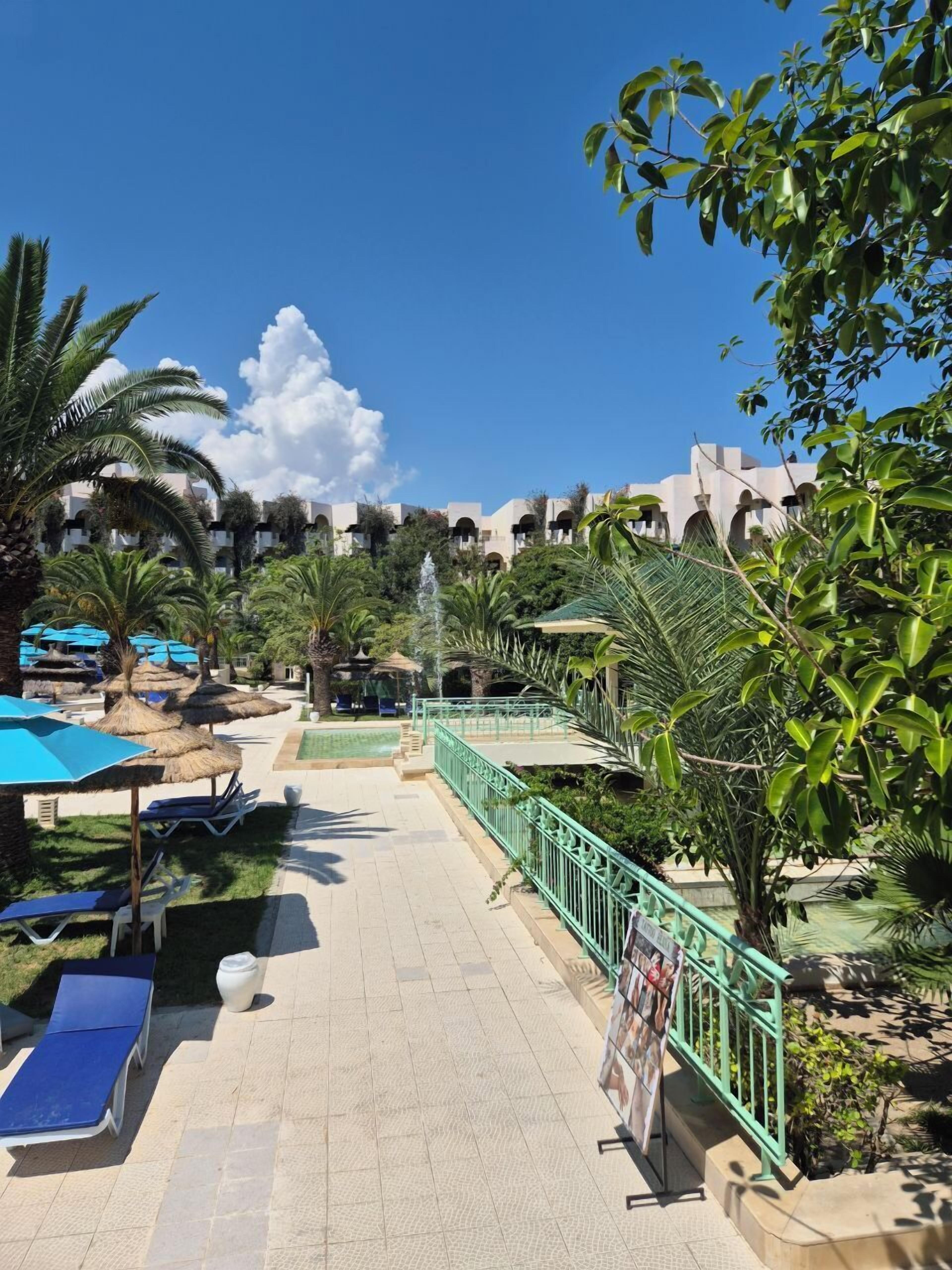 Zwembad van een resort met ligbedden, parasols en een fontein.