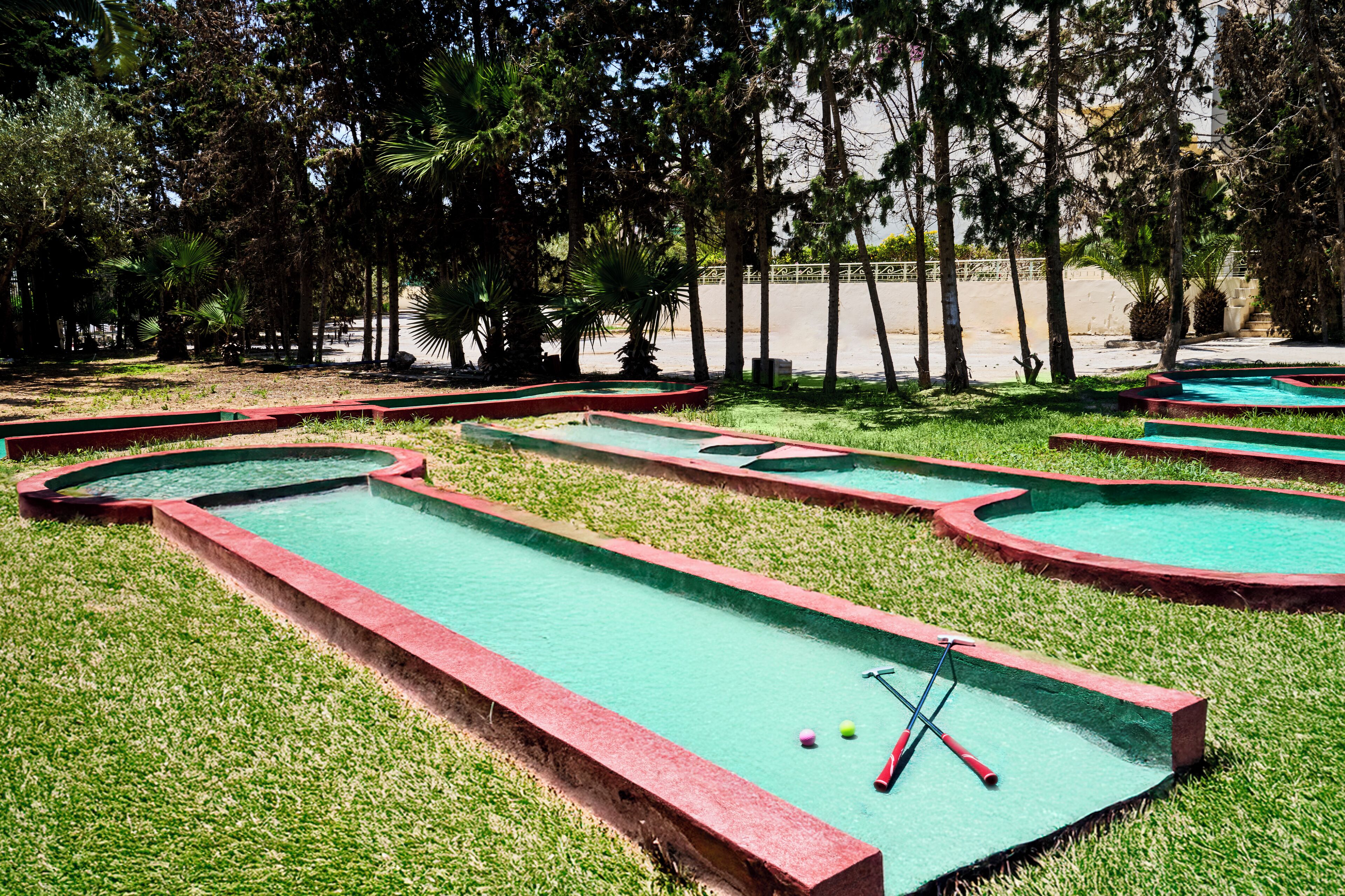 A miniature golf course with multiple green putting areas and red borders.