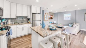 A modern kitchen with white cabinets, a marble island, and bar stools. - Seahorse Suites #3. Island Living at it's Best! (Sanibel)