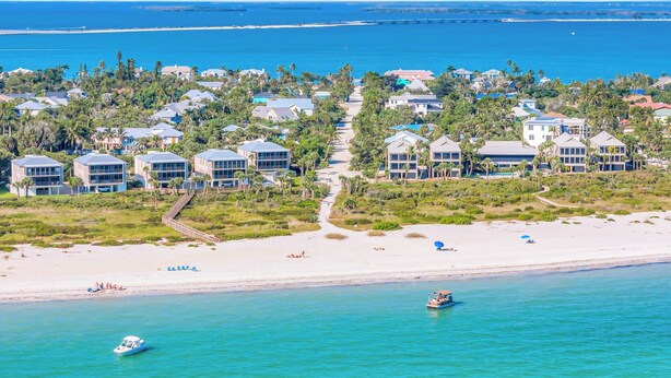 An aerial view of a coastal resort with beachfront villas, a sandy beach, and clear blue waters. - Seahorse Suites #3. Island Living at it's Best! (Sanibel)