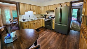 A modern kitchen with wooden cabinets, a stainless steel refrigerator, and a gas stove. - The Marigold Cottage: Serene Mountain Getaway w/ Fire Pit, Large Yard (Highlands)