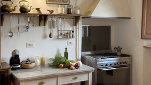 Una cocina con estufa, horno y varios utensilios colgados en la pared.