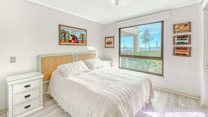 Una camera da letto con una grande finestra, un letto, un comodino e elementi decorativi alle pareti.